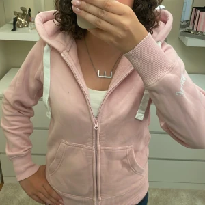 Ljusrosa hoodie från Russemerch - Säljer en ljusrosa hoodie från Russemerch med vit logga på ärmen. Tröjan har huva med vita snören, dragkedja framtill och två stora fickor. Mjukt material och ribbade muddar vid ärmslut och nederkant. Perfekt för chill dagar och häng med kompisar. Super skön och har använt kanske 10 gånger 