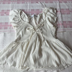 Vit top med knyt rosett  - Supersöt vit topp med volangärmar och knyt framtill. 