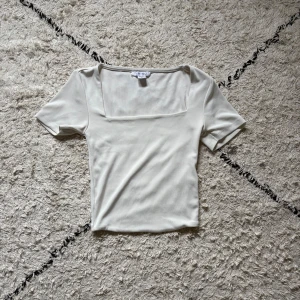 Vit ribbad topp med fyrkantig hals - Snygg vit topp från Amisu i storlek XS med ribbad struktur och fyrkantig halsringning. Kortärmad och figurnära passform som ger en clean och modern vibe. Perfekt att styla med jeans eller kjol för en fräsch look. Kolla sista bilden för att se defekten på toppen!🤗❤️