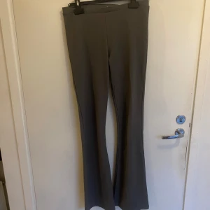 Grå bootcut byxor  - Snygga grå byxor med bootcut-snitt som ger en schysst siluett. Byxorna har en hög midja och är tillverkade i ett mjukt och följsamt material, perfekt för dig som gillar stilrena och klassiska vibes. Passar till både sneakers och boots.