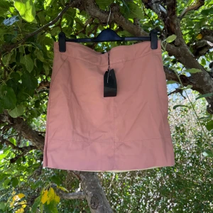 Rosa kortkjol i mocka, storlek 42 - Supersnygg rosa kortkjol från Only i mjuk skinnliknande material. Storlek 42 men kan vara något liten. Kjolen har enkel design med sömmar framtill och är helfärgad utan mönster. Insidan är beige och känns skön mot huden. Perfekt för dig som gillar stilrena plagg med lite edge. Helt ny med tags/ prislapp fortfarande kvar. 