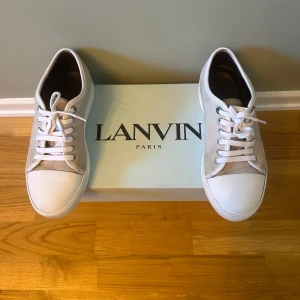Lanvin grå sneakers i mocka - Snygga sneakers från Lanvin i ljusgrå mocka med vita detaljer och snörning. Skorna har rund tå och platt sula, vilket ger en clean och stilren vibe. Perfekta för dig som gillar minimalistisk design och exklusiva material. Uk 6/41-42