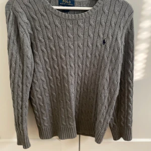 Grå stickad Polo ralph lauren tröja - Tena, säljer min stickade polo Ralph lauren tröja som är grå färgad. Tröjan är i bra skick och är i barn storlek L (14-16 år).                                                                        Hör av er vid minsta lilla fundering!  /mvh William 