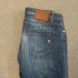 Blå jeans från Dondup Bakony - Snygga blå jeans från Dondup, modell Bakony, tillverkade i Italien. Jeansen har klassisk femficksdesign, bruna detaljer och en slim passform med lätt tvättad look. Passar 150-160cm. Inga fel 