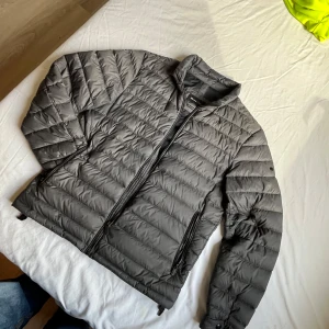 Massimo Dutti dunjacka - Storlek S men passar även M.                            Snygg grå dunjacka från Massimo Dutti med stilren design och horisontella quiltade paneler. Jackan har dragkedja framtill, två sidofickor med dragkedja och en liten ståkrage