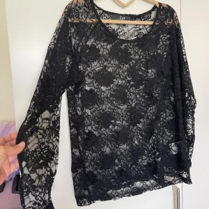 Svart spetsblus från ZAY - Svart transparent blus från ZAY med lång ärm och vackert blommigt spetsmönster. Blusen har rund halsringning och är perfekt för dig som gillar en edgy och romantisk stil. Superfin att styla lager på lager eller med ett linne under.Använd en gång.Storlek märkt som S men jag använde på mig och jag är M i storlek 