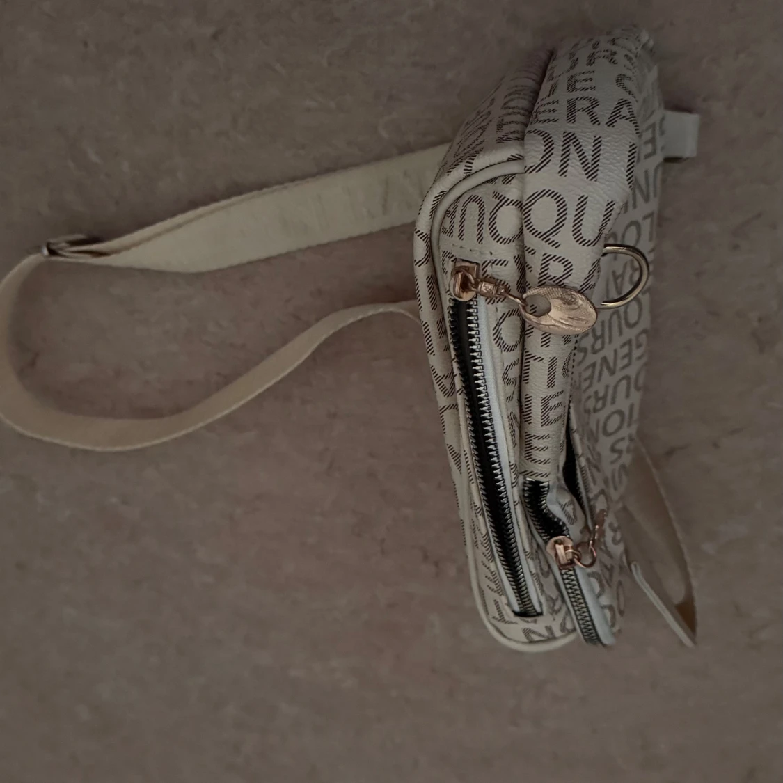 Beige axelväska med textmönster - 1