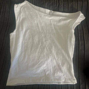 Vit oneshoulder topp från ONLY - Säljer en vit oneshoulder topp från ONLY i mjuk bomull. Toppen har en clean och enkel design med asymmetrisk axel, vilket ger en cool och modern vibe. Perfekt att styla med jeans eller kjol för en trendig look. Passar dig som gillar minimalistiskt och stilrent. Oanvänd, ej prislapp kvar!