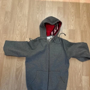 Grå hoodie från Burberry med röd huva - Snygg grå hoodie från Burberry. Helt oanvänd, priset kan diskuteras vid smidig affär🙌. 