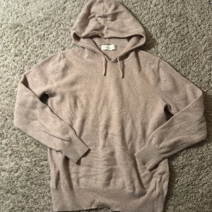 Beige cashmere hoodie från Sayless - Mjuk och lyxig hoodie i beige cashmere från Sayless. Tröjan har huva med snörning, ribbade muddar och långärmad design. Perfekt för dig som gillar chill och stilren look med exklusiv känsla. Passar dig som vill ha något extra comfy och snyggt.