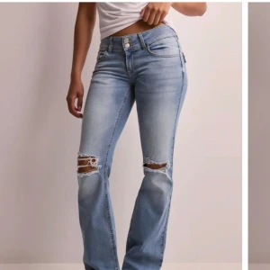 Bootcut ljusblå jeans  - Säljer ett par ljusblå bootcut jeans från Nelly med snygga slitningar över knäna. Jeansen har två knappar i midjan, klassiska fickor fram och bak med lock och knapp, samt en lätt tvättad look. Perfekt för dig som gillar en avslappnad och trendig stil. Nypris på jeansen är 700kr, tvättar jeansen innan de skickas. Skriv här på plick för frågor. 