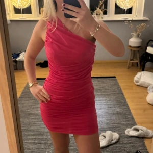 Rosa one shoulder klänning från Zara - Säljer en snygg rosa kortklänning från Zara med one shoulder-design. Klänningen har tight passform och draperade detaljer som ger en cool look. Perfekt för dig som vill sticka ut med färg och stil!