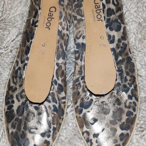 Leopardmönstrade ballerinaskor från Gabor - Säljer ett par ballerinaskor från Gabor med leopardmönster i metallictoner. Skorna har rund tå och platt sula, perfekt för dig som vill ha något både snyggt och bekvämt.