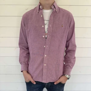 Ljuslila oxfordskjorta från Ralph Lauren M - Säljer en ljuslila oxfordskjorta från Ralph Lauren i slim fit. Skjortan har klassisk button-down krage, broderad logga på bröstet och vita knappar. Perfekt för dig som gillar stilrena och snygga skjortor.