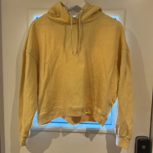 Gul croppad hoodie från 157 - Säljer en ljusgul croppad hoodie från 157 i storlek M. Tröjan har huva med dragsko och långa ärmar med muddar. Perfekt för en avslappnad och trendig look.