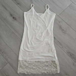 Vit spetsklänning från Saint Tropez - Säljer en vit klänning från Saint Tropez med smala axelband och v-ringning. Klänningen har en fin spetsdetalj längst ner och är ärmlös. Storlek S💞