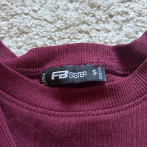 Vinröd ribbad långärmad tröja från FB Sister - Säljer en vinröd långärmad tröja från FB Sister i storlek S. Tröjan är ribbad och har en rund halsringning. Perfekt att styla till jeans eller kjol för en enkel och snygg look.