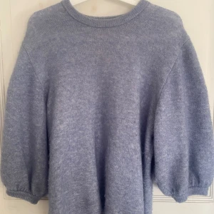 Blå stickad tröja - Mysig blå stickad tröja med rund halsringning och ballongärmar. Tröjan har en avslappnad passform och ribbade muddar vid ärmslut och hals. Från Stylein!