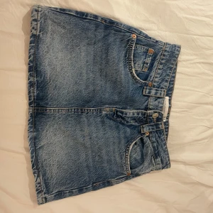 Jeanskjol från Stradivarius - Säljer en klassisk blå jeanskjol från Stradivarius med femficksdesign och synliga sömmar. Kjolen har bälteshällor, knapp och dragkedja framtill samt två bakfickor. Strl 34 men liten i storlek