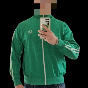 Grön track jacket från Fred Perry - Tja! Nu säljer jag en Fred Perry track top som är i mycket gott skick, använd ett par gånger. Perfekt för dig som vill vara stiligast på läktaren eller kanske studenten? Fler bilder kan skickas om så önskas! MVH Viggo 