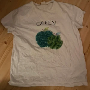Vit t-shirt med tryck från Zara Kids - Vit t-shirt från Zara Kids med tryck av gröna buskar och texten 'GREEN' på bröstet. Klassisk passform och rund halsringning. Perfekt för en avslappnad stil.