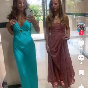 Turkos långklänning med ringdetalj - Säljer en turkos långklänning med djup v-ringning och en snygg ringdetalj framtill. Klänningen har smala axelband och är ärmlös, med en slät och glansig yta som ger en lyxig känsla. Perfekt för bal! Kan mötas upp! Skicka bud så godkänner jag! Storlek 36/S. 