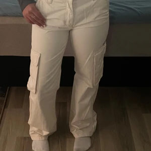 Beiga cargobyxor - Säljer ett par beiga cargobyxor från GinaTricot med raka ben och stora fickor på sidorna. Byxorna har normal passform och är tillverkade i bomull. Perfekta för en avslappnad och trendig stil.