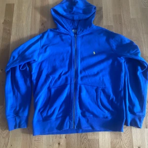 Blå hoodie från Polo Ralph Lauren - Large - Säljer en blå hoodie från Polo Ralph Lauren med dragkedja och huva. Mycket bra skick, knappt använd, köpt på loppis.