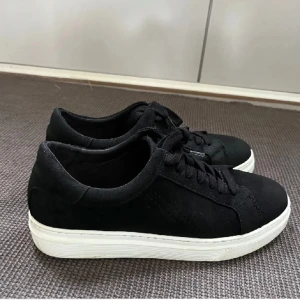 Svarta sneakers med vit sula - Säljer ett par stilrena svarta sneakers i mocka med vit sula. De har klassisk snörning och är i mycket bra skick. Perfekta för både vardag och fest! Passar till det mesta och är superbekväma. Storlek 40/41