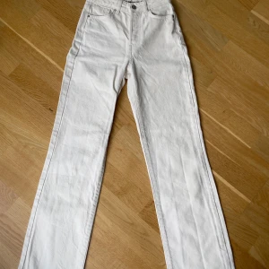 Vita raka jeansbyxor - Säljer ett par vita jeansbyxor med raka ben och hög midja.Perfekta för en clean och stilren look. Använd 1-2ggr