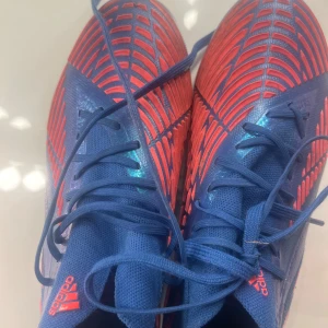 Blå och rosa fotbollsskor från Adidas - Säljer ett par snygga fotbollsskor från Adidas i blått med rosa detaljer och blåa skosnören, tror det är i storlek 39!