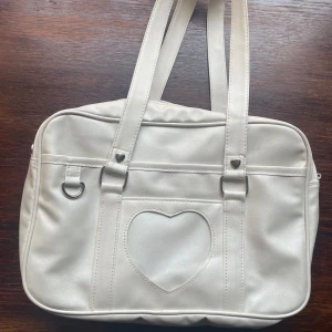 Coquette väska - En superfin väska som är perfekt till skolan! Måtten är ungefär 30cm på längden och 24cm på höjden. Tyvärr har insidan slitits sönder lite, men det påverkar inte funktionen! Det är även tre små hål på framsidan, men de går knappt att se :)