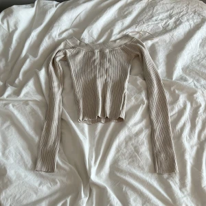 Beige ribbad långärmad topp från BikBok - Säljer en beige ribbad långärmad topp från BikBok. Toppen har en croppad passform och bredare halsringning. Perfekt att styla med jeans eller kjol för en trendig look.