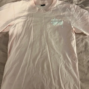 Ljusrosa t-shirt från Stüssy - Säljer en ljusrosa t-shirt från Stüssy med vitt tryck på bröstet och ryggen. Strl S🩷