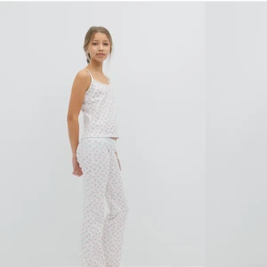 Vit linnepajamas, med tillhörande pyjamas byxor  med rosa nallemönster - Säljer ett vitt linne med smala axelband, tillhörde byxor med  rosa/ röda nallemönster. Perfekt för mysiga hemmakvällar eller sommarens varma nätter. Mjukt material och avslappnad passform. Storlek är 158/164 men passar mig som bär xs/ s 