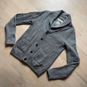 Stickad Cardigan med Fickor - En stilren och skön kofta perfekt för våren eller sommarkvällar med knappar och fickor. Storlek S passar även M! Om ni har frågor eller funderingar är det bara att höra av sig!