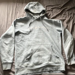 Ljusblå hoodie från Sail Racing - Säljer en ljusgrå hoodie från Sail Racing med broderad logga på bröstet och huvan. Tröjan har känguruficka framtill och justerbar dragsko i huvan. Perfekt för en avslappnad stil. Den är i bra skick 9/10 använd fåtal gånger