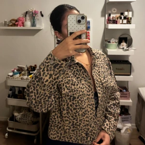 Leopardmönstrad jeansjacka - Säljer en jeansjacka från Gina Tricot med leopardmönster. Jackan har knappar framtill, två bröstfickor och är i en beige och svart färg. Perfekt för dig som vill sticka ut lite extra. Endast testad så den är ny utan prislapp.