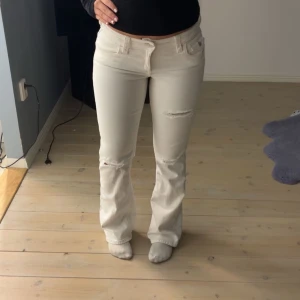 Vita bootcut jeansbyxor från Gina Tricot - Säljer ett par vita jeansbyxor från Gina Tricot med bootcut-passform. Byxorna har klassiska fem fickor, knappar och dragkedja framtill samt slitna detaljer på benen. Haft på mig en gång, inga defekter alltså💞