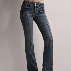 Low Waist Bootcut Pocket Jeans - Snygga blå jeans med bootcut passform. Klassiska fickor fram och bak samt markerad söm längs benen. Perfekta för en trendig och avslappnad look.