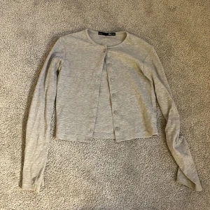 Ljusgrå ribbad kofta från 157 - Säljer en ljusgrå ribbad kofta från 157 i storlek XS. Koftan har långa ärmar, rund halsringning och knäppning framtill med små knappar. Perfekt att slänga över en topp för en enkel och stilren look.Inga tecken på användning💕
