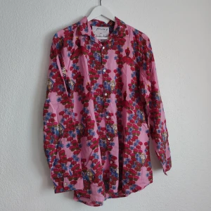 Blommig skjorta från Foresta 9 - Färgglad skjorta med blommigt mönster i rosa, blått och rött från Foresta 9. Skjortan har lång ärm, klassisk krage och knäppning framtill. Perfekt för dig som vill sticka ut med en unik stil.