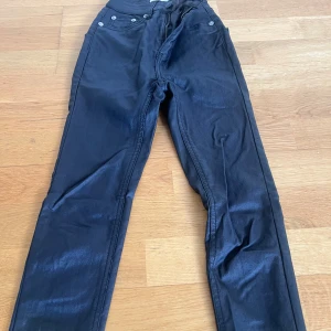 Svarta jeansbyxor från 157 - Svarta jeansbyxor från 157 med klassisk femficksdesign och silverfärgade nitar. Byxorna har normal passform och stängs med knapp och dragkedja. Perfekta till många olika stilar.