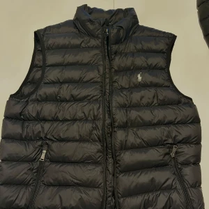 Svart dunväst från Polo Ralph Lauren - Säljer en svart dunväst från Polo Ralph Lauren. Västen är i stort sätt oanvänd. Meddela mig vid frågor🙌