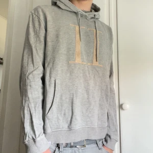 Grå hoodie från Les Deux - Säljer en grå hoodie från Les Deux med stor broderad logga på bröstet. Tröjan är väll omhändertagen och är i storlek L. Lägg bud eller köp direkt