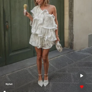 Vit volangklänning med spets och oneshoulder - Superfin vit kortklänning med volanger och spetsdetaljer. Klänningen är från årets kollektion med Lojsan, aldrig använd med lappar kvar 🤍🤍🤍