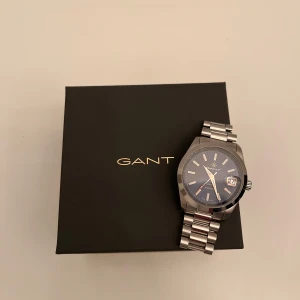 Gant Eastman klocka - Säljer en stilren klocka från GANT med silverfärgad länk och marinblå urtavla. Klockan har datumvisning och levereras i originalförpackning. Den är som ny och funkar perfekt! Nypris ligger på ca 2700kr