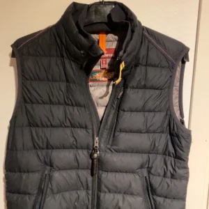 Mörkblå dunväst från Parajumpers - Mörkblå dunväst från Parajumpers med dragkedja och hög krage. Västen har en broderad logga på baksidan och är allmänt superlätt, 9/10 skick. Säljs pga att det inte är min stil längre 🙌🏼🙌🏼