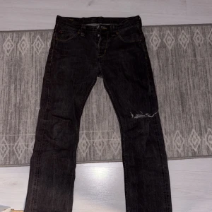 Grå jeans från Lee - Säljer ett par gåra jeans från Lee med klassisk femficksdesign och guldfärgade sömmar. Jeansen har en rak passform och är tillverkade i slitstarkt denim. Perfekta för en avslappnad stil.