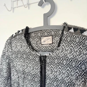 Svartvit mönstrad jacka från La Redoute - Använd ett fåtal gånger. Snygg svartvit jacka från pull & bear med ett geometriskt mönster. Jackan har långa ärmar och en dragkedja framtill. Den är dekorerad med fransar vid kanterna och har två fickor med dragkedjor.